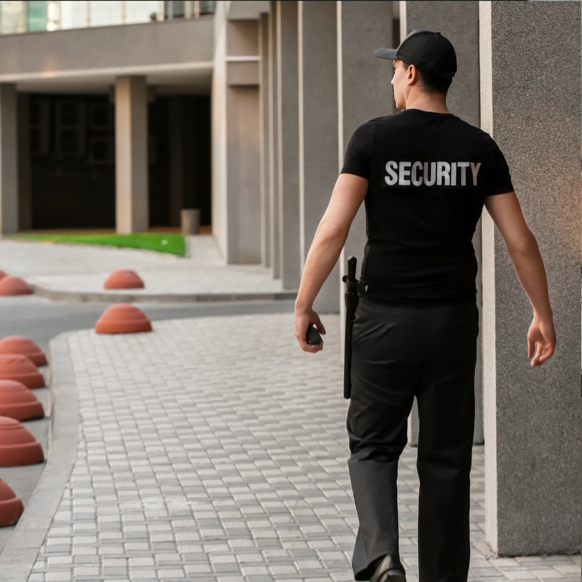 Un agent de sécurité en uniforme sombre, avec l’inscription « SECURITY » dans le dos.
