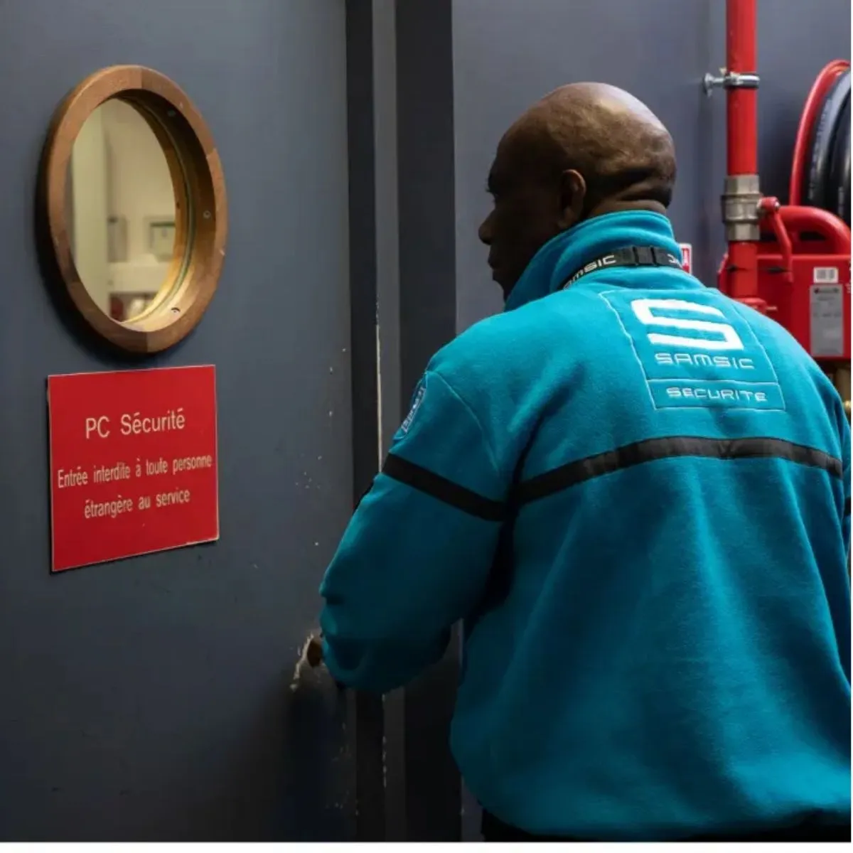 Un agent de sécurité incendie en uniforme bleu vérifie la porte d’un local technique. Un agent de sécurité incendie en uniforme bleu.
